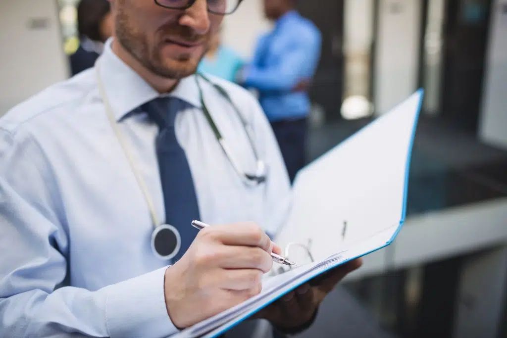 Doctor writing a medical report in hospital corridor