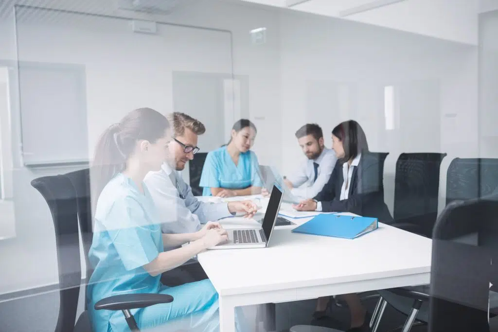 Doctors discussing over laptop in meeting at conference room, offshore medical office solutions