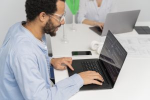 Close‑up of a medical coder’s hands typing on a laptop with code