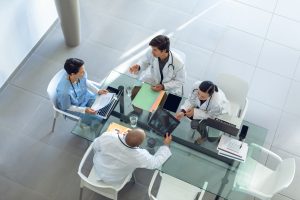 High angle view of diverse medical team discussing with each other at the table of conference room in hospital, offshore medical office solutions