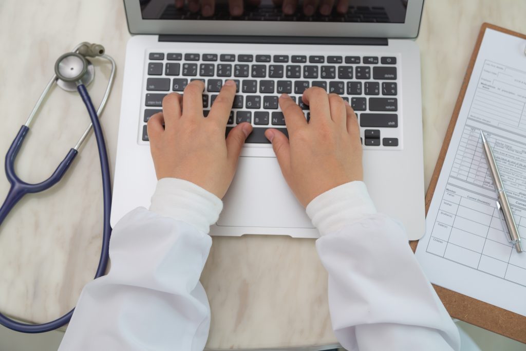 Doctor hands typing on laptop keyboard, virtual medical message management