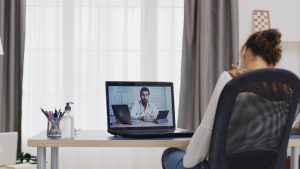 Woman in a remote video call with her doctor using tablet computer, virtual clinic operations support