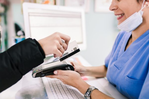 A patient paying using a credit card at a medical billing counter.