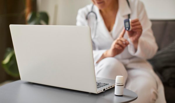 Female doctor demonstrating how to use an oximeter for online patient monitoring.