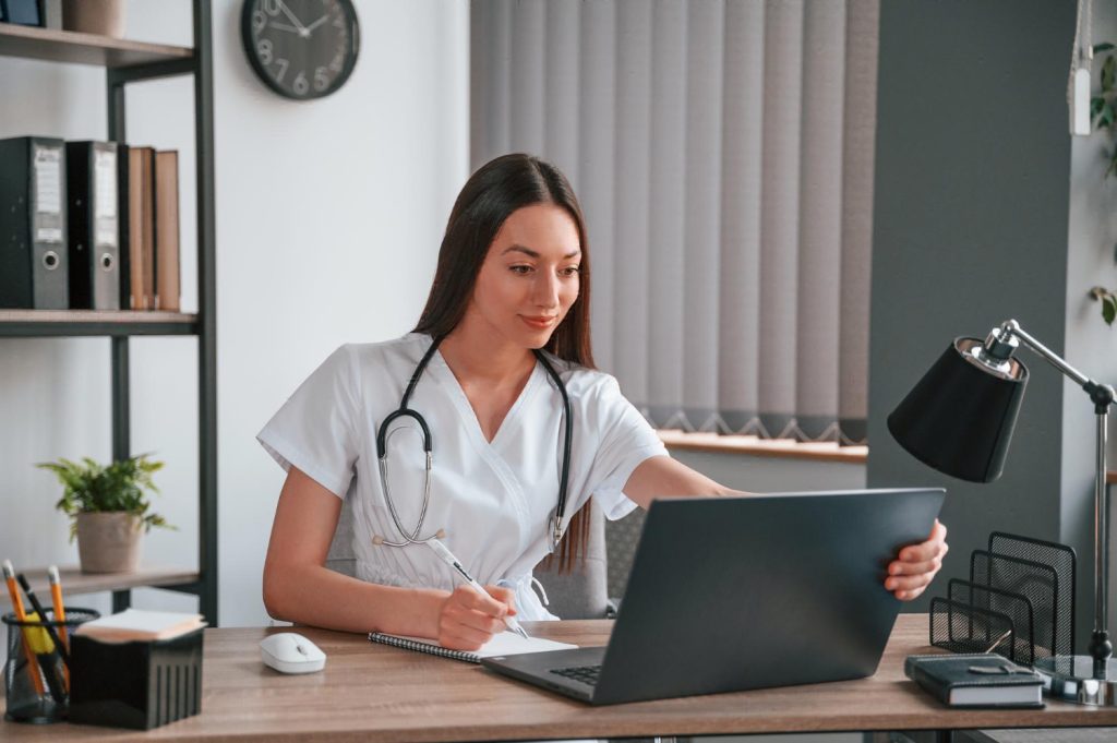 Female sitting at table working on laptop for benefits of remote patient monitoring.