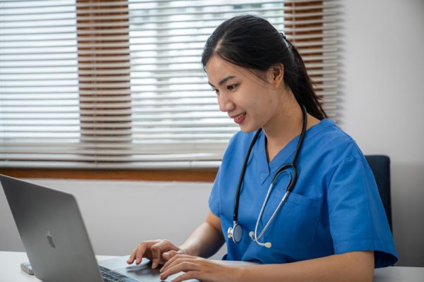 Female virtual assistant providing the best virtual assistant services for medical practice, using a laptop for online patient consultation and messaging.