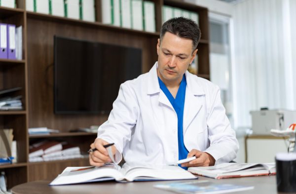 Male medical scribe doing paper works in his table
