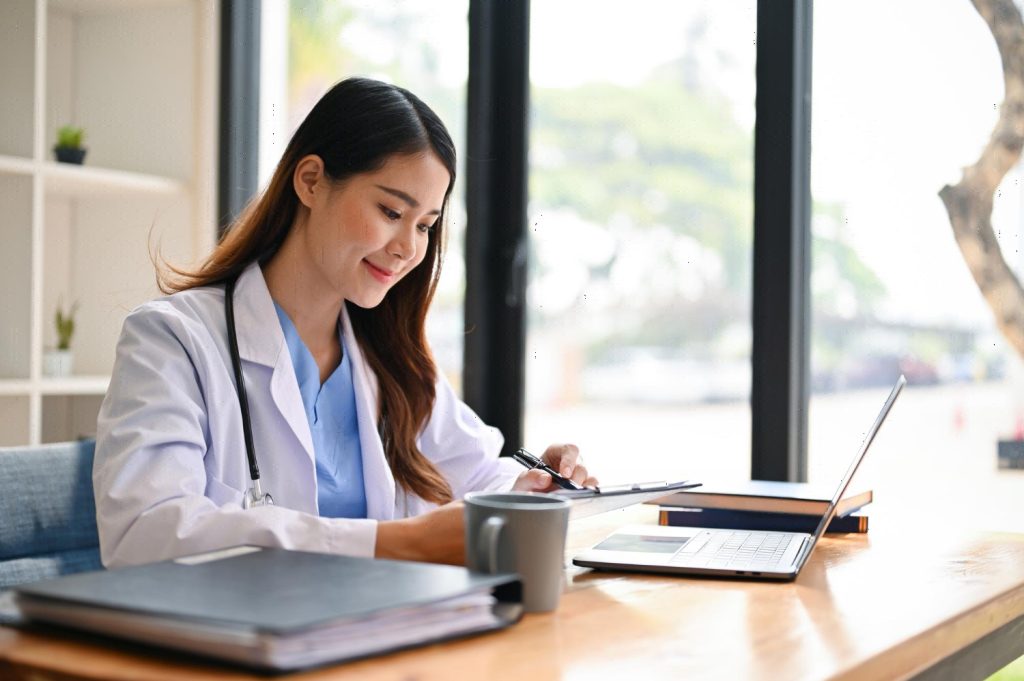 Medical scribe duties include reading her medical cases at her desk in a hospital office.