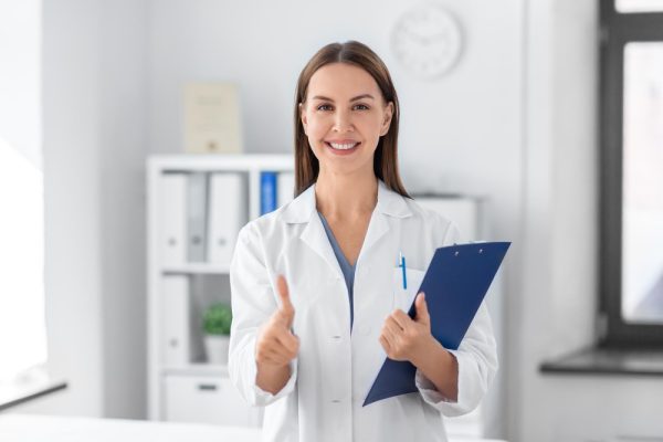 Medical scribe smiling holding a clipboard with thumbs up.