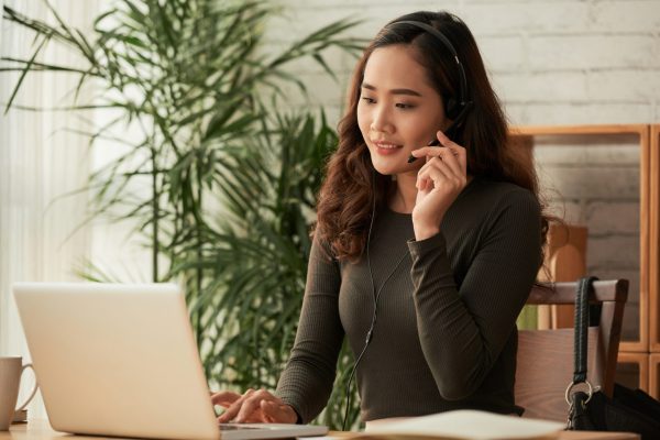 Smiling business woman in headset consuting clients