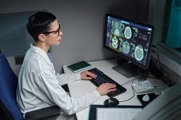 Neurologist analyzing medical images on computer screen in laboratory.
