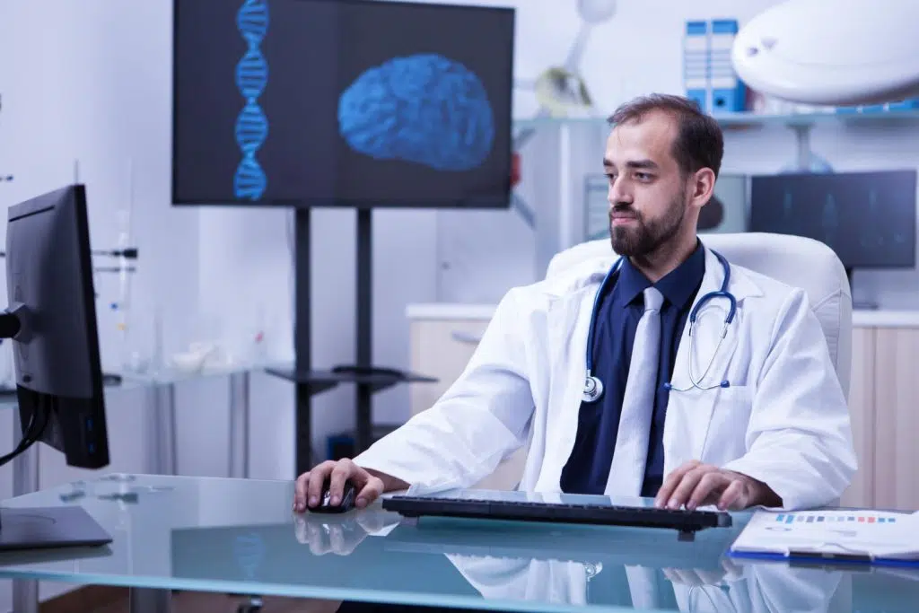 Neurology medical billing specialist working on computer with mouse and keyboard