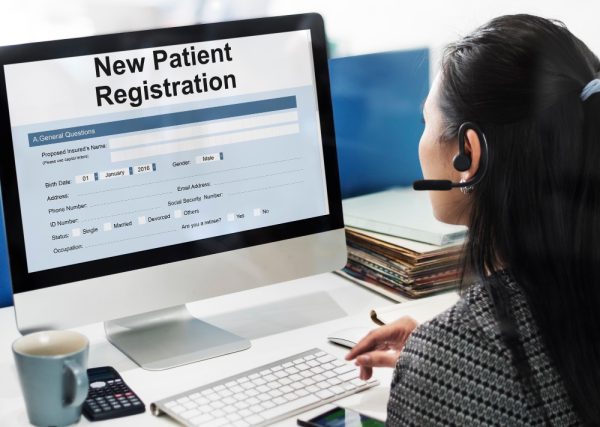 Patient access representative working on a computer, entering patient access information form.