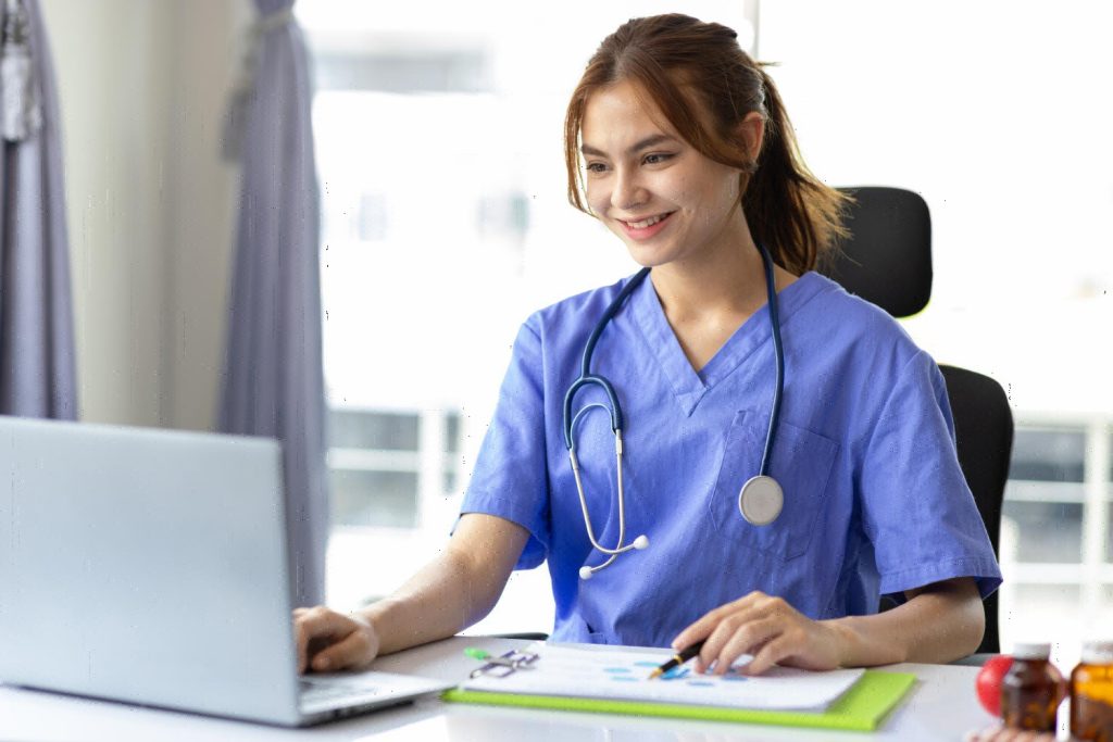 Patient coordinator job description, working on a laptop in a hospital office.
