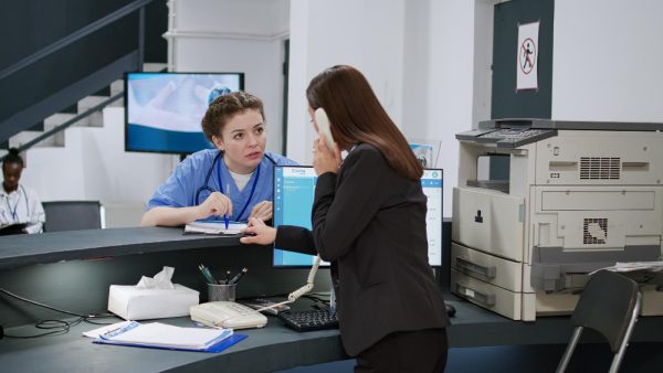 Receptionist talking to medical assistant at hospital
