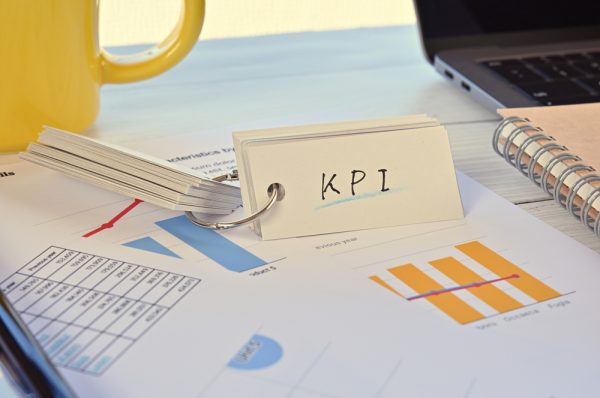 There's a word book on a desk cluttered with papers. The word KPI is written in it.