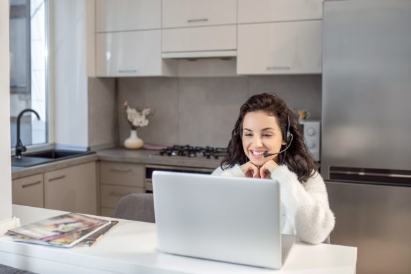 Virtual assistant wearing a headset while working on a laptop from home.
