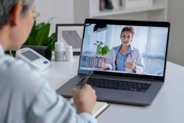 Woman using laptop for online consultation about the benefits of remote patient monitoring in her living room.