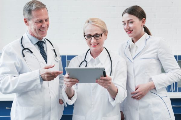 three doctors standing while looking patient record