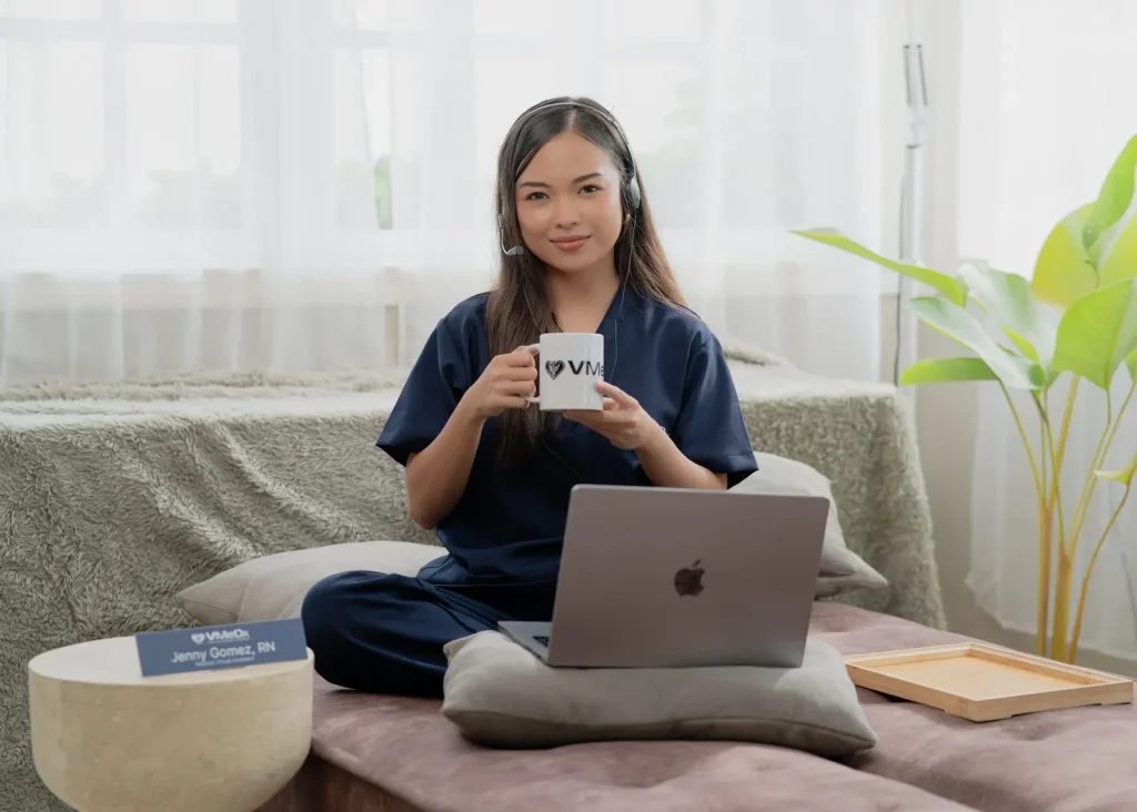 Female remote medical scribe specialist holding a cup, wearing headset while working on her laptop