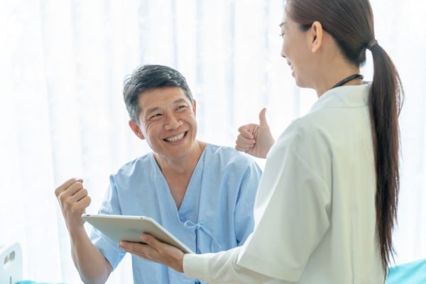 Happy patient at hospital discussing health with remote patient monitoring specialist.