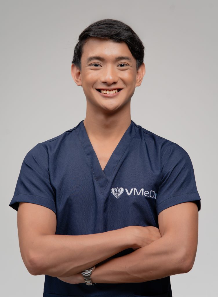 Male remote patient monitoring specialist in medical scrubs with crossed arms smiling confidently