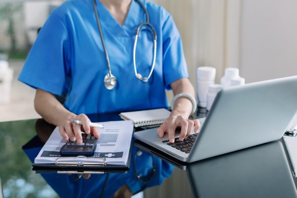 Medical billing assistant using calculator, smartphone, and tablet to manage hospital medical costs.