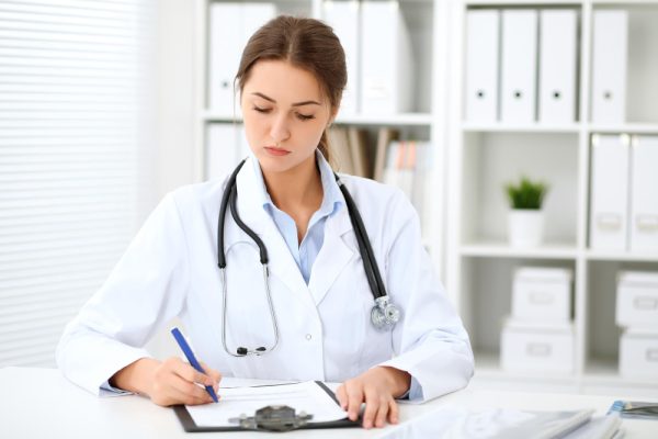 Remote health data organization, female doctor working at hospital office desk, managing healthcare and insurance records.