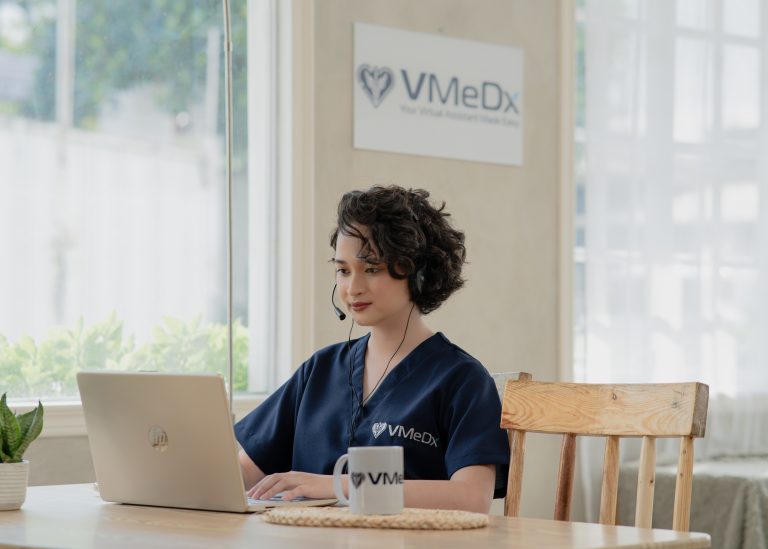 Remote patient monitoring specialist wearing headset while working on laptop at desk